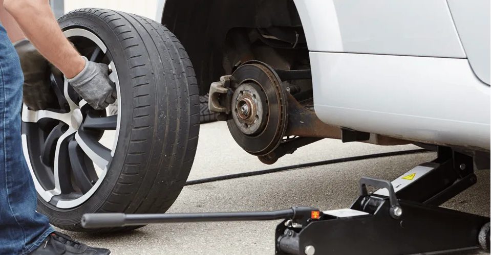 Man with gloves replacing new car tyre